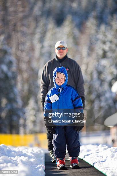 father and son riding "magic carpet" ski escalator - 空飛ぶ絨毯 ストックフォトと画像