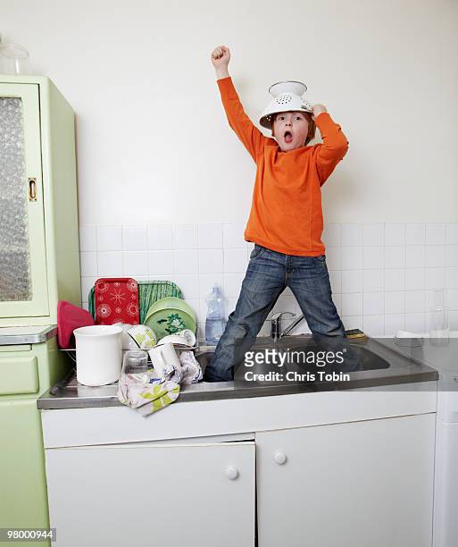 boy standing in sink with colander helmet - misbehaving children stock pictures, royalty-free photos & images