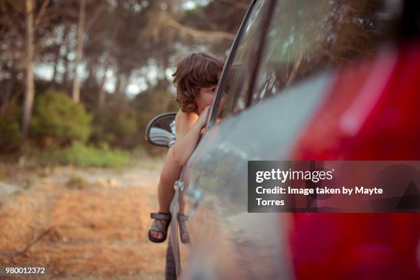 boy escaping from a car through the window - vista dalla parte posteriore di un veicolo foto e immagini stock