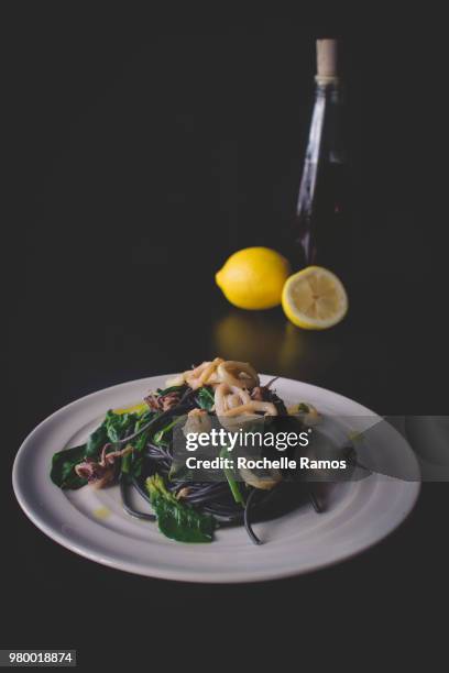 black squid ink pasta with lemon calamari rings and spinach - squid ink pasta stock pictures, royalty-free photos & images