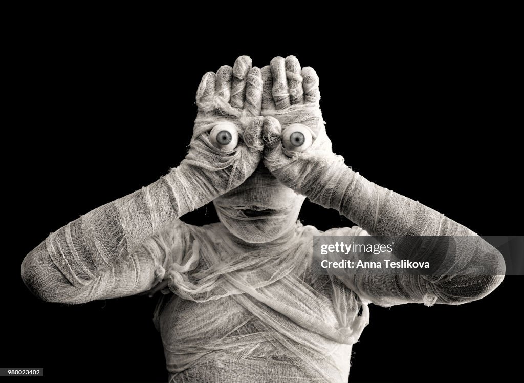 Man wearing mummy costume with eyeballs on hands