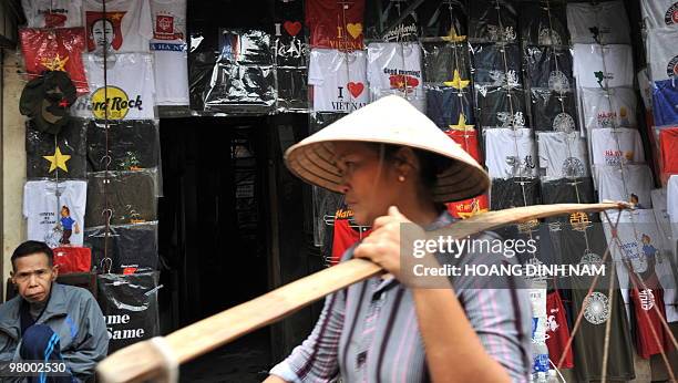 Street vendor walks past a facade of a shop covered with T-shirts in the tourist quarter of Hanoi on March 19, 2010. AFP PHOTO/HOANG DINH Nam