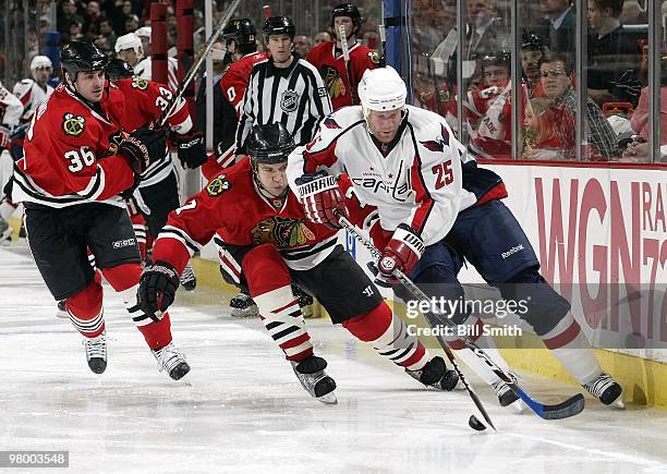 Jason Chimera of the Washington Capitals skates with the puck as Brent Seabrook of the Chicago Blackhawks reaches for the puck from behind and Dave...