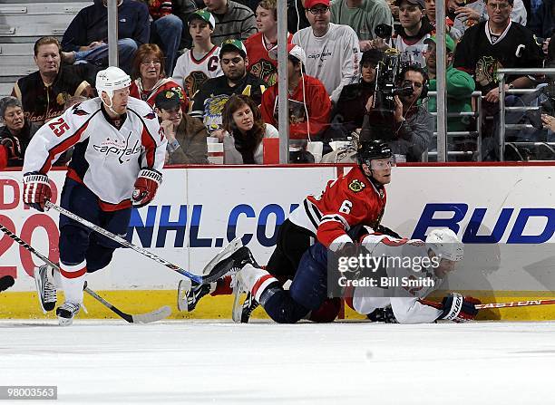 Jordan Hendry of the Chicago Blackhawks falls on top of Mike Knuble of the Washington Capitals as Jason Chimera of the Capitals skates behind during...