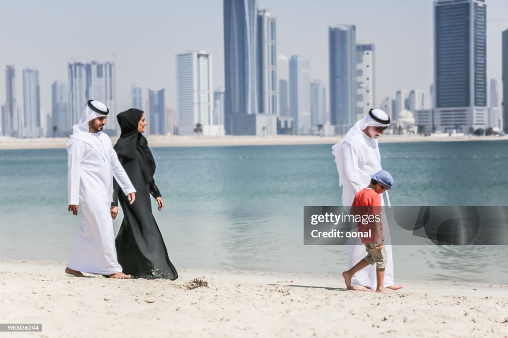 Arabische Familie, die zu Fuß am Strand im Herbst