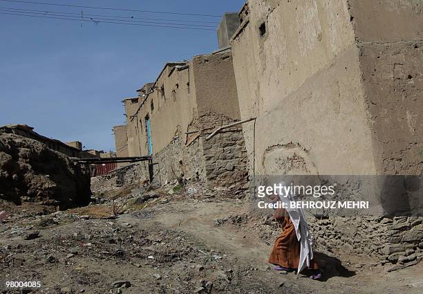 An Afghan woman carries her child from her home in the old city of Kabul on March 15, 2010. A three-day nationwide polio eradication signature...