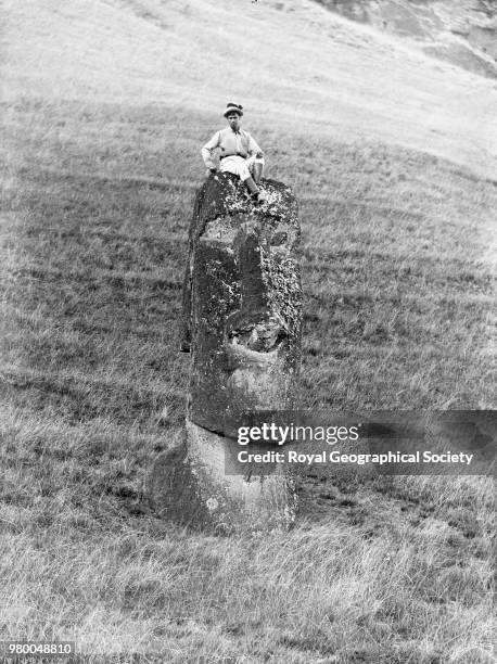 View of a tall statue, Rano Raraku, View of a tall statue standing in the outer slopes of the statue quarry Rano Raraku. The boy on top is for scale,...