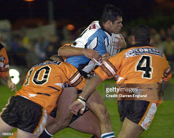 Chris McKenna of the Cronulla Sharks is tackled by Graham Cotter and Jason Bulgarelli of the East Coast Tigers during the NRL trial game played...