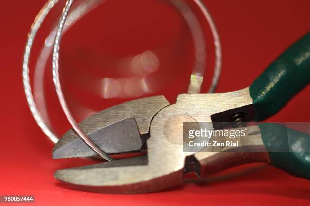 wire cutter plier and framers hanging wire on red background - draadtang stockfoto's en -beelden