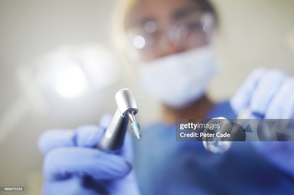 Dentist looking down on camera with tools in hand