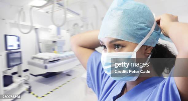 doctor tying mask in operating room - ready fokus blick in die kamera stock-fotos und bilder