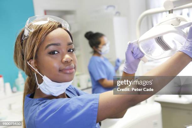 dentist adjusting light over chair - dental assistant stock pictures, royalty-free photos & images