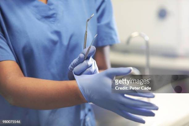 dentist putting gloves on - dentistas fotografías e imágenes de stock