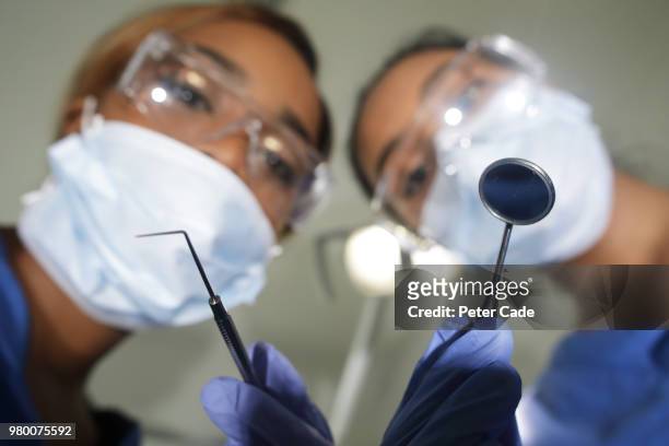 dentists looking down on camera with tools in hand - rimotore di placca foto e immagini stock