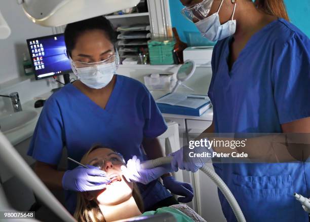 dentist working on patient in chair - igienista dentale foto e immagini stock