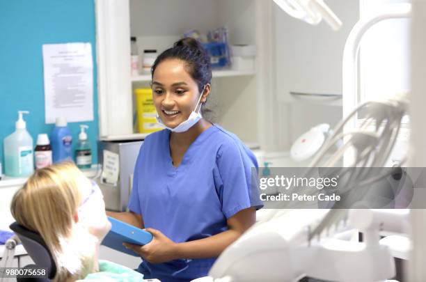 dentist talking to patient in chair - tandpijn stockfoto's en -beelden