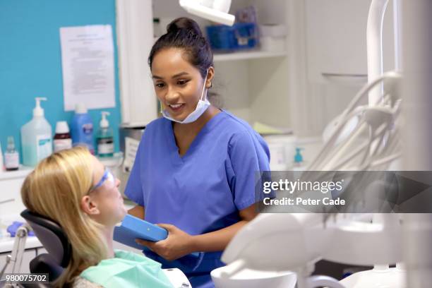 dentist talking to patient in chair - dental assistant stock pictures, royalty-free photos & images