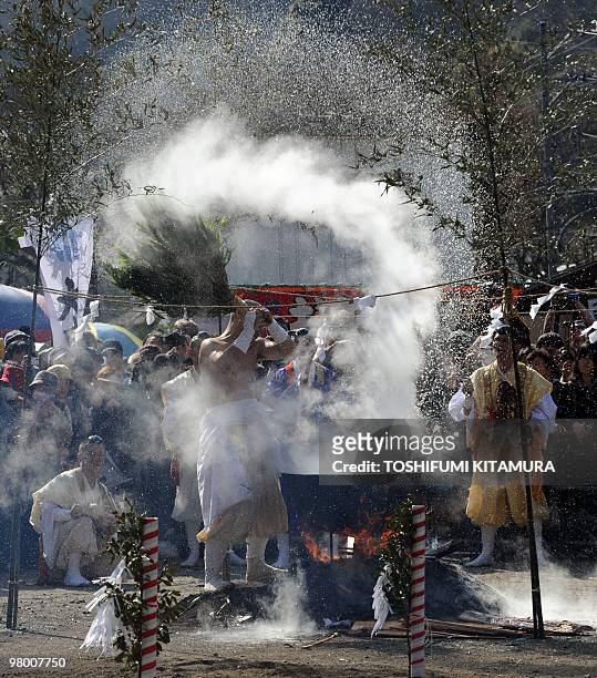 Buddhist ascentic monk sprays hot water with tree branches prior to the "Hi-watari" or fire walking ritual ceremony to herald the coming of spring at...