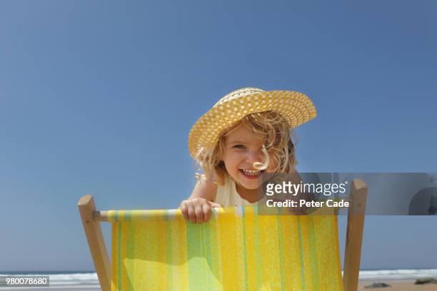 young girl looking over back of deck chair on beach - beach girl ストックフォトと画像