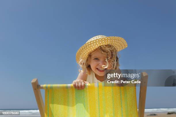 young girl looking over back of deck chair on beach - alleen kinderen stockfoto's en -beelden