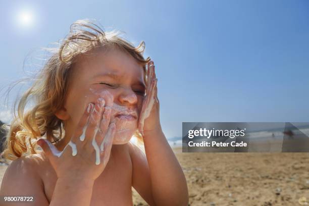 toddler girl applying suncream - quemado por el sol fotografías e imágenes de stock