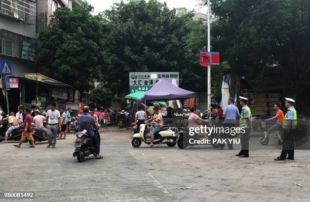 Police officers monitor dog sellers during the Yulin dog meat festival at the Dashichang market in Yulin in China's southern Guangxi region on June...