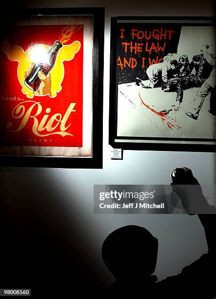 An exhibitor cleans the glass on a Banksy picture at Glasgow Art Fair on March 24, 2010 in Glasgow, Scotland. Held in George Square in the heart of...