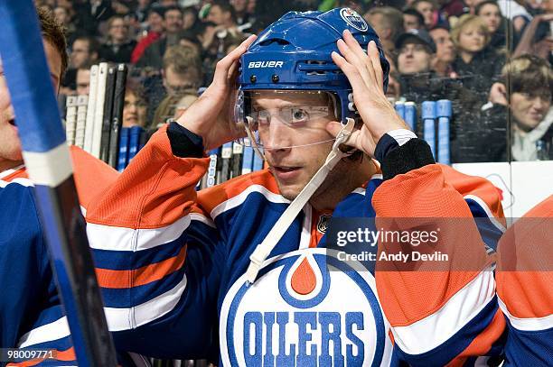 Tom Gilbert of the Edmonton Oilers puts on his helmet prior to a game against the Vancouver Canucks at Rexall Place on March 23, 2010 in Edmonton,...