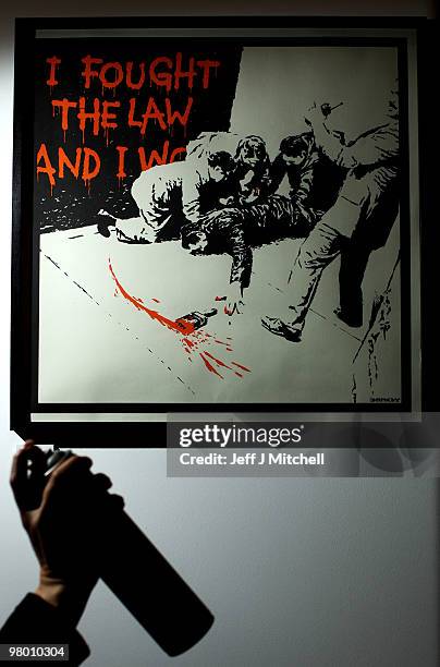 An exhibitor cleans the glass on a Banksy picture at Glasgow Art Fair on March 24, 2010 in Glasgow, Scotland. Held in George Square in the heart of...