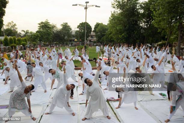 Indian yoga practitioners take part in a yoga session on International Yoga Day in Amritsar on June 21, 2018. - Downward-facing dogs, cobras and...