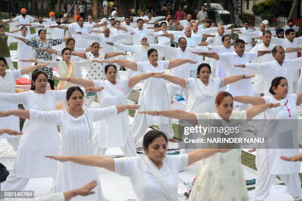 Indian yoga practitioners take part in a yoga session on International Yoga Day in Amritsar on June 21, 2018. - Downward-facing dogs, cobras and...