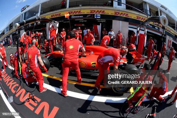 Pit crew members change tires of Ferrari's Finnish driver Kimi Raikkonen's car during the preparation of the practice session at the Circuit Paul...