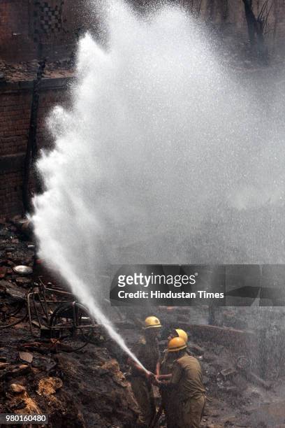 Fire fighters douse flames at a slum cluster near Sadar Bazar where a major fire broke out, on June 14, 2008 in New Delhi, India.
