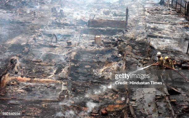 Fire fighters douse flames at a slum cluster near Sadar Bazar where a major fire broke out, on June 14, 2008 in New Delhi, India.