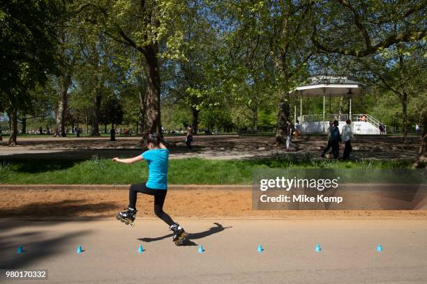 Young girl practices her slalom inline skating technique in Hyde Park in London, England, United Kingdom. People gather to walk along the promenade...