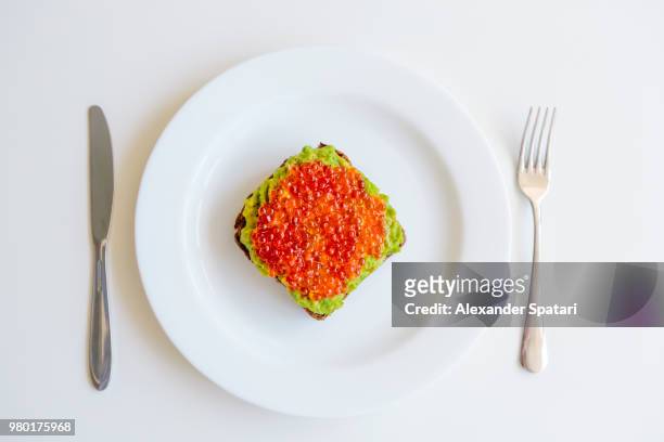 avocado toast with red caviar on top, directly above view - kaviar stock-fotos und bilder