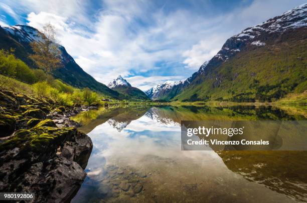 scenic mountain valley reflecting in lake, nordfjord, norway - olden foto e immagini stock