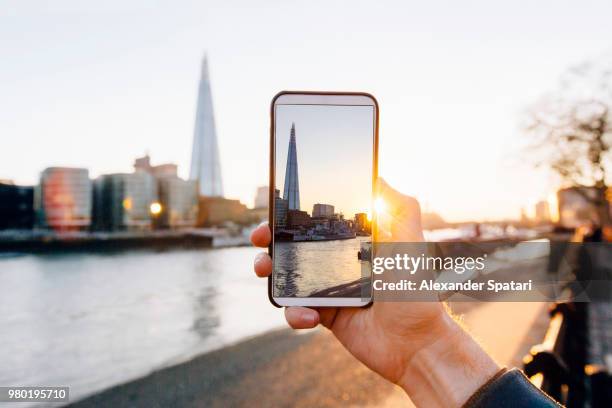 man taking pictures of london skyline with his smartphone, personal perspective view - photographing sunset stock pictures, royalty-free photos & images