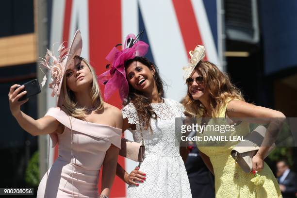 Women pose for a selfie on Ladies Day at the Royal Ascot horse racing meet, in Ascot, west of London, on June 21, 2018. - The five-day meeting is one...