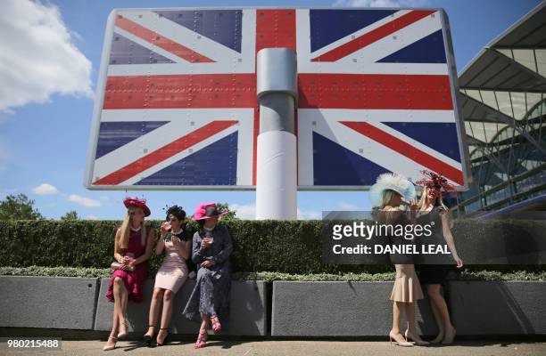Racegoers pose for a photograph in front of a large Union flag poster at Ladies day at the Royal Ascot horse racing meet, in Ascot, west of London,...