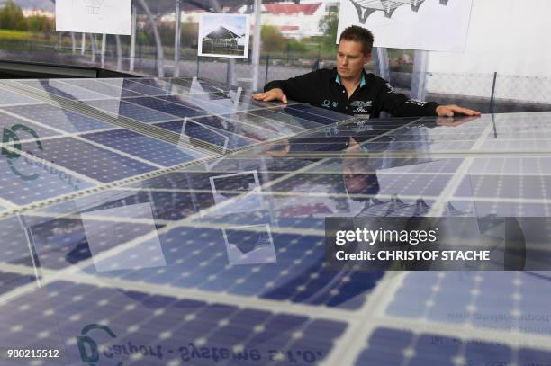 An employee watches the model of a solar panel system at the roof of a carport which is presented at the booth of a German company at the InterSolar...