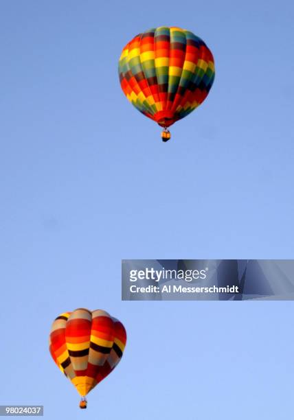 Hot air balloons fly overhead during a morning ascent into blue skies at the Albuquerque International Balloon Fiesta on October 8, 2005.