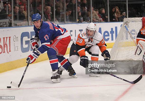 Brandon Dubinsky of the New York Rangers skates with the puck in front of Jack Hillen of the New York Islanders at Madison Square Garden on March 24,...