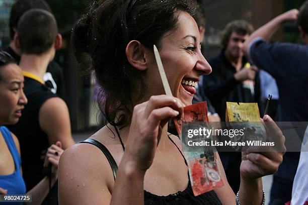 Asli Karakaya holds money that she smashed from a 400 kilogram ice block at Martin Place on March 25, 2010 in Sydney, Australia. The ice block held...