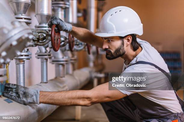 worker with helmet in front of pipes with valves - distillation tower stock pictures, royalty-free photos & images