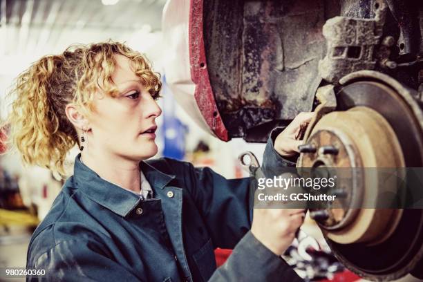 weibliche mechaniker ersetzt den bremsbelag - equal pay stock-fotos und bilder