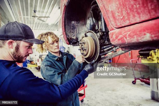 team of auto mechanics working on a old car at their garage - minimum wage stock pictures, royalty-free photos & images