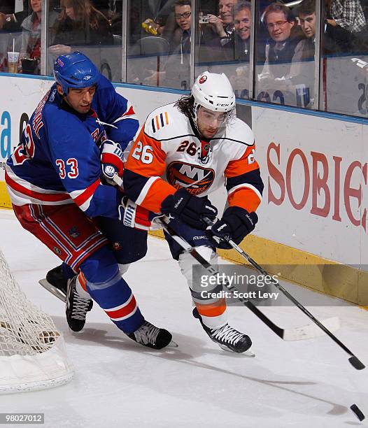Matt Moulson of the New York Islanders skates behind the net with the puck under pressure by Michal Rozsival of the New York Rangers on March 24,...