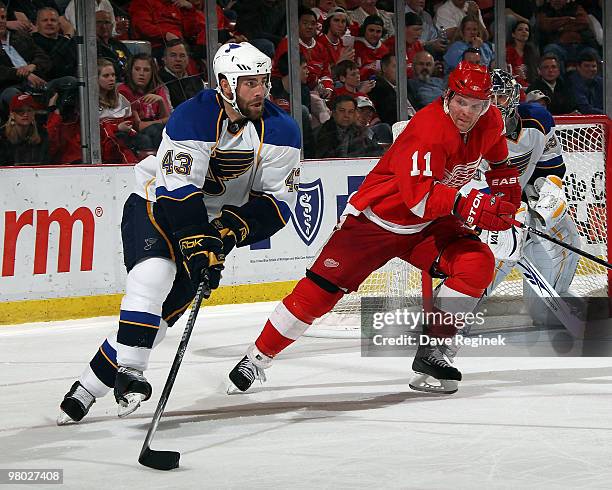 Mike Weaver of the St. Louis Blues tries to keep the puck away from Dan Cleary of the Detroit Red Wings during an NHL game at Joe Louis Arena on...