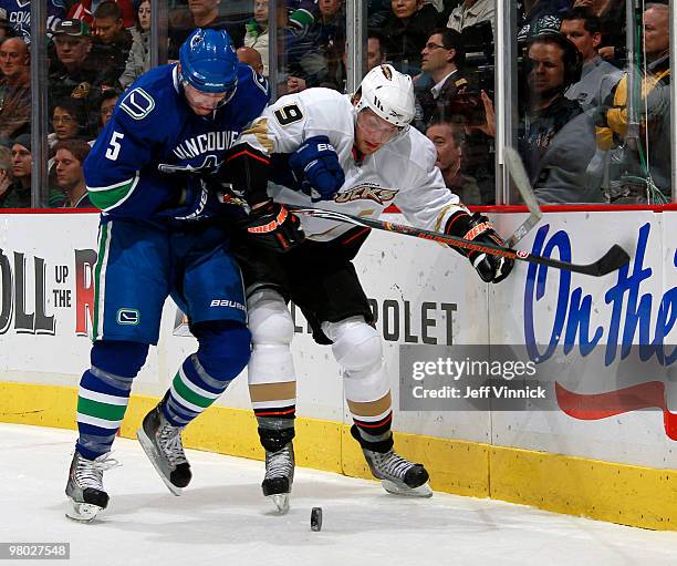 Christian Ehrhoff of the Vancouver Canucks and Bobby Ryan of the Anaheim Ducks battle for the loose puck along the end boards during their game at...